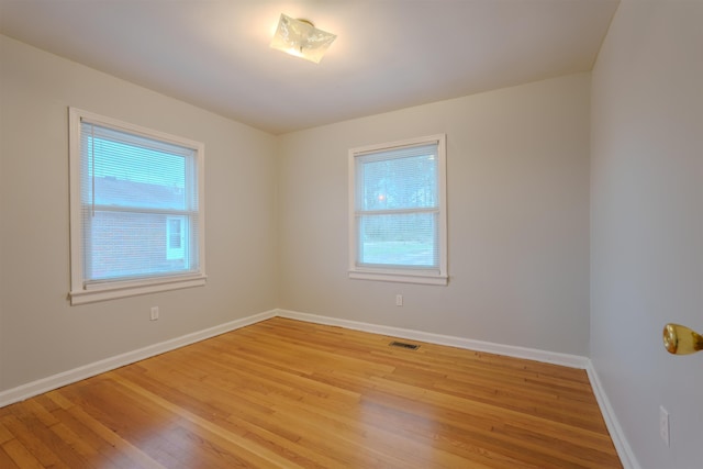 spare room with light wood-style floors, visible vents, plenty of natural light, and baseboards