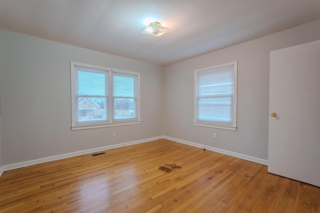 unfurnished room featuring light wood-type flooring, visible vents, and baseboards