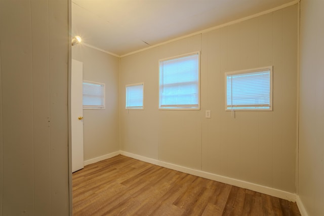 unfurnished room with ornamental molding, baseboards, and wood finished floors