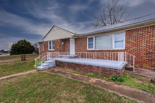 view of front of property featuring metal roof, a front lawn, and brick siding