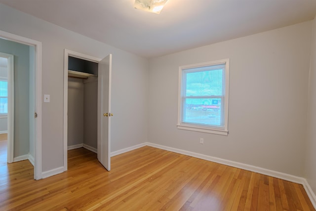 unfurnished bedroom featuring a closet, light wood-type flooring, and baseboards