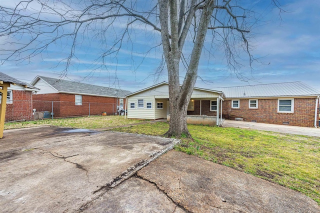 rear view of house with brick siding, crawl space, fence, and a lawn