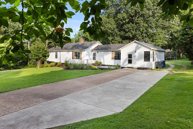  - ranch-style house with a trampoline, driveway, and a front lawn