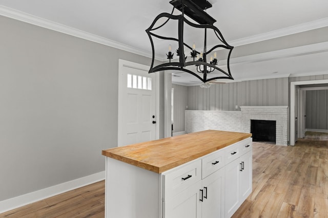  - kitchen featuring wooden counters, ornamental molding, white cabinets, a chandelier, and light wood finished floors
