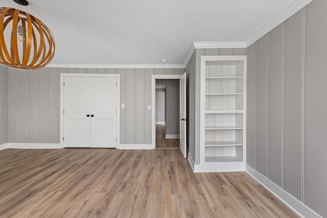  - unfurnished bedroom with wood finished floors, ornamental molding, and a closet