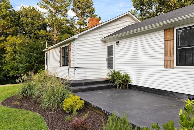  - view of property exterior featuring a patio and a chimney