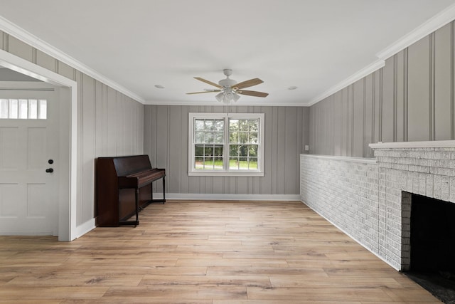  - unfurnished living room featuring light wood-type flooring, a ceiling fan, ornamental molding, and a brick fireplace