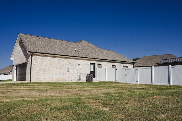 rear view of house featuring a lawn and a garage