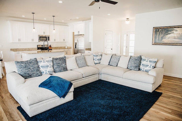 living room with ceiling fan and light hardwood / wood-style flooring