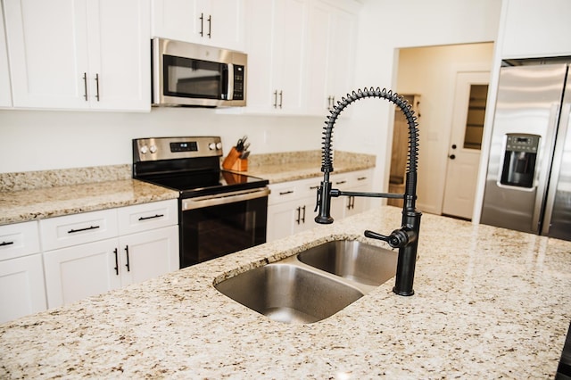 kitchen with light stone counters, sink, and stainless steel appliances