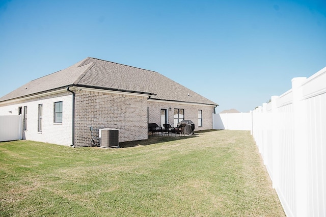 rear view of property featuring cooling unit, a yard, and a patio