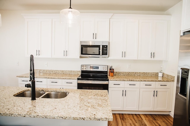 kitchen with pendant lighting, white cabinets, sink, light hardwood / wood-style floors, and stainless steel appliances