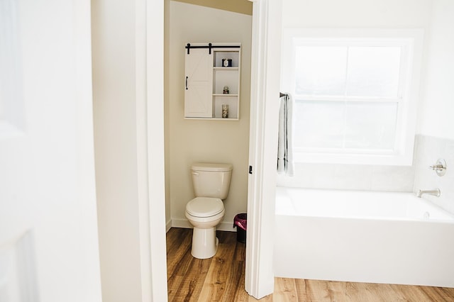 bathroom featuring hardwood / wood-style floors, a bathtub, and toilet