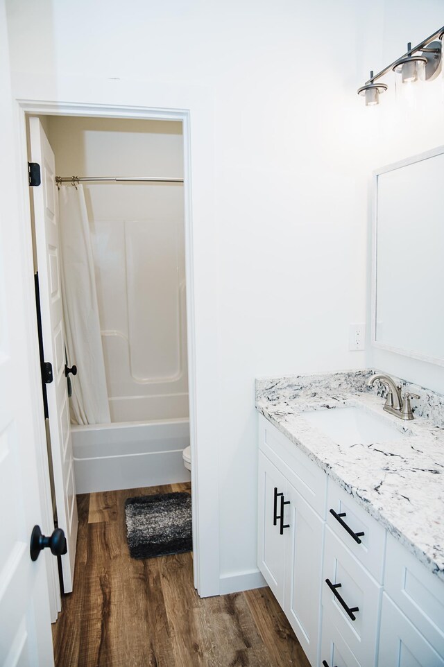 full bathroom with shower / bathtub combination with curtain, vanity, wood-type flooring, and toilet