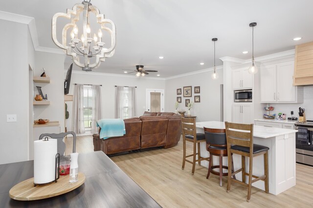 kitchen featuring a center island, white cabinets, ceiling fan with notable chandelier, decorative light fixtures, and stainless steel appliances