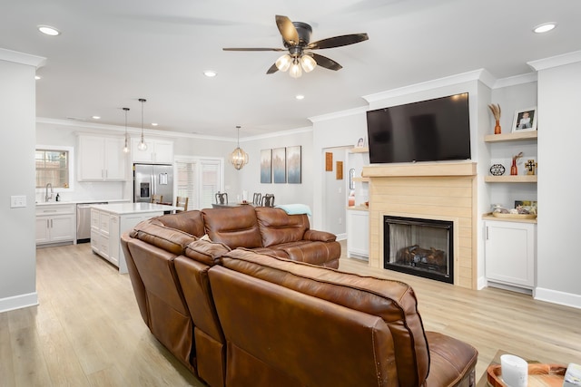 living room with ceiling fan, sink, crown molding, and light hardwood / wood-style flooring