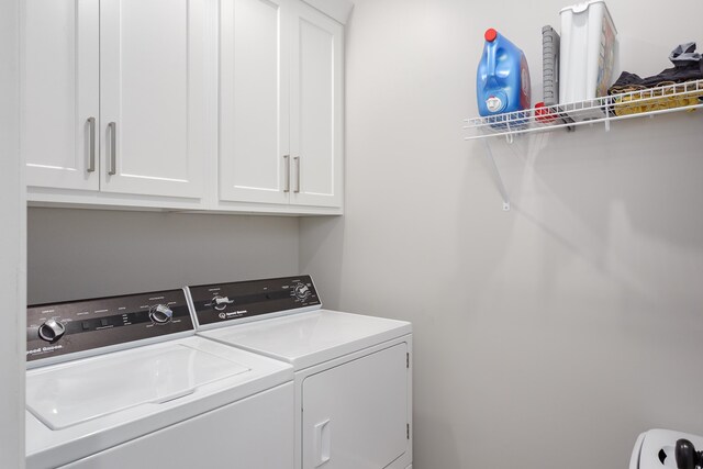 washroom with cabinets and washing machine and clothes dryer