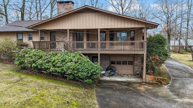 exterior space featuring brick siding, driveway, a chimney, and an attached garage