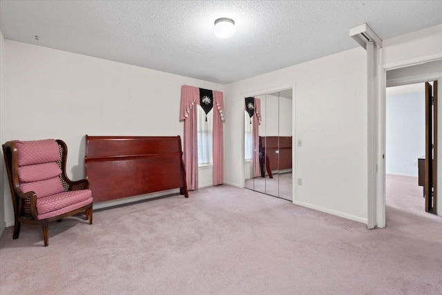 sitting room featuring carpet flooring, a textured ceiling, and baseboards