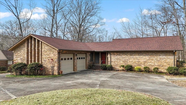 view of front of house featuring a garage, driveway, roof with shingles, and brick siding