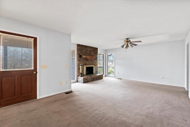 unfurnished living room with a ceiling fan, visible vents, baseboards, a brick fireplace, and carpet