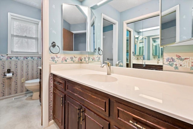 bathroom with toilet, visible vents, a textured ceiling, and vanity