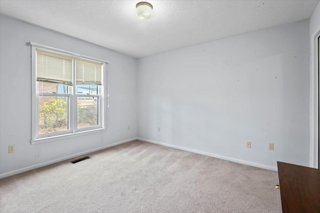 carpeted spare room with visible vents, a textured ceiling, and baseboards