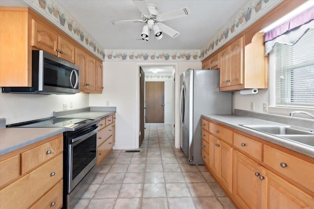 kitchen with stainless steel appliances, light countertops, a sink, and a ceiling fan