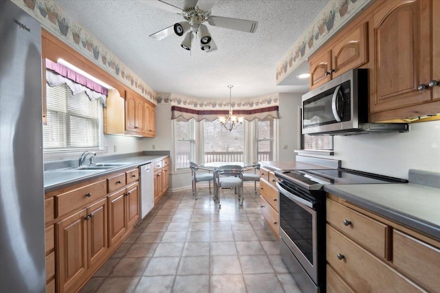 kitchen featuring a textured ceiling, ceiling fan with notable chandelier, stainless steel appliances, a sink, and decorative light fixtures