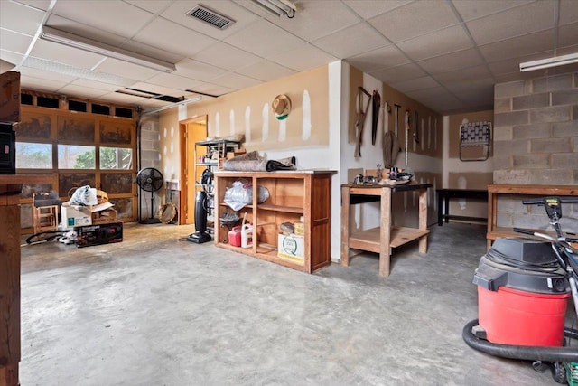 miscellaneous room featuring visible vents, a garage, a paneled ceiling, and unfinished concrete floors