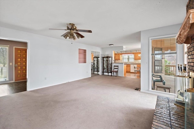 unfurnished living room featuring a ceiling fan, light colored carpet, and visible vents