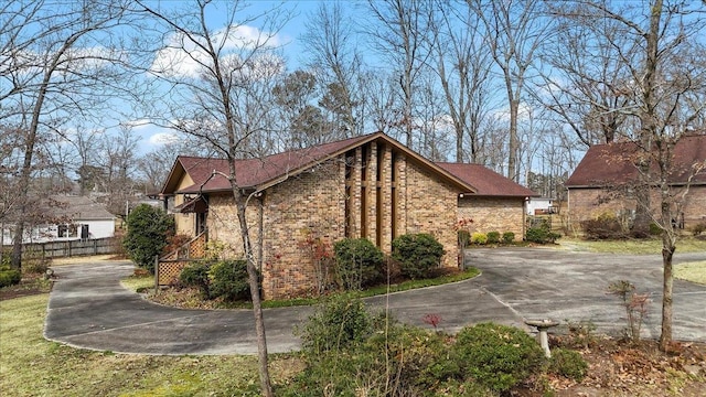 view of home's exterior with brick siding, fence, and driveway