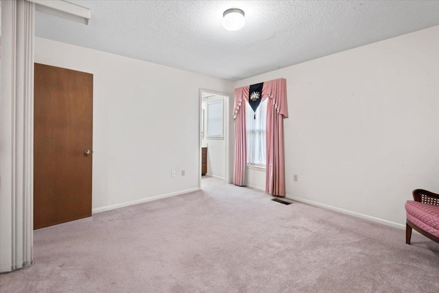 interior space featuring a textured ceiling, carpet floors, visible vents, and baseboards