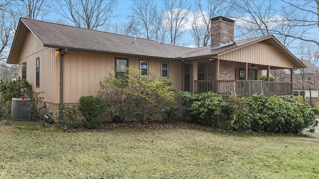 rear view of house featuring a yard, a chimney, a shingled roof, central AC unit, and ceiling fan