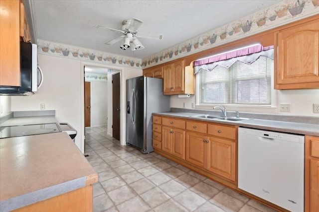 kitchen with a textured ceiling, stainless steel appliances, a sink, and light countertops