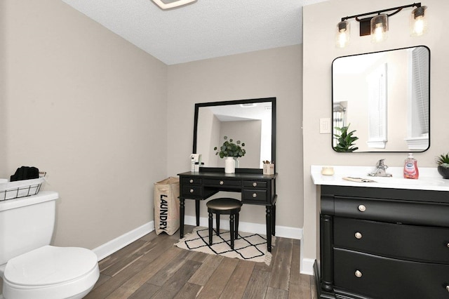 bathroom with toilet, vanity, a textured ceiling, and hardwood / wood-style flooring