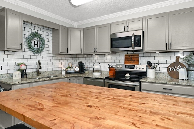 kitchen featuring gray cabinetry, sink, a textured ceiling, butcher block countertops, and stainless steel appliances