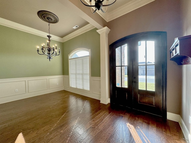 entryway featuring french doors, dark hardwood / wood-style flooring, ornate columns, ornamental molding, and a chandelier