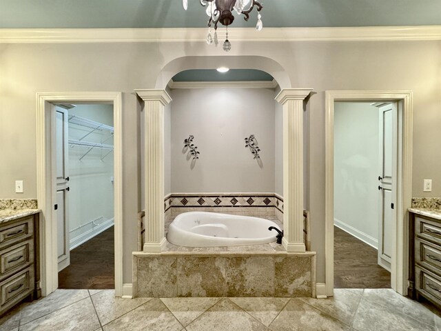 bathroom with vanity, decorative columns, crown molding, and tiled tub