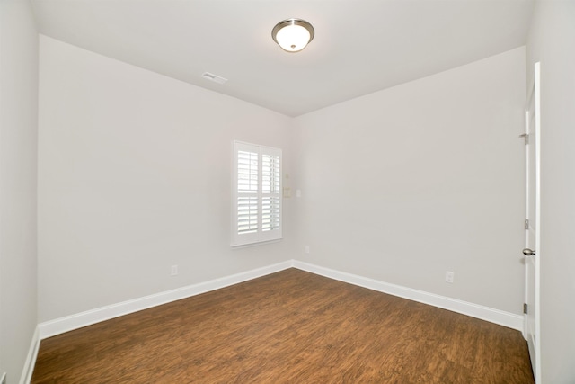  - empty room with baseboards, visible vents, and dark wood-type flooring
