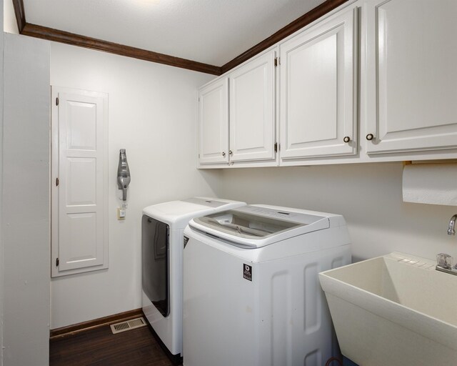 clothes washing area featuring cabinets, sink, ornamental molding, and washing machine and dryer