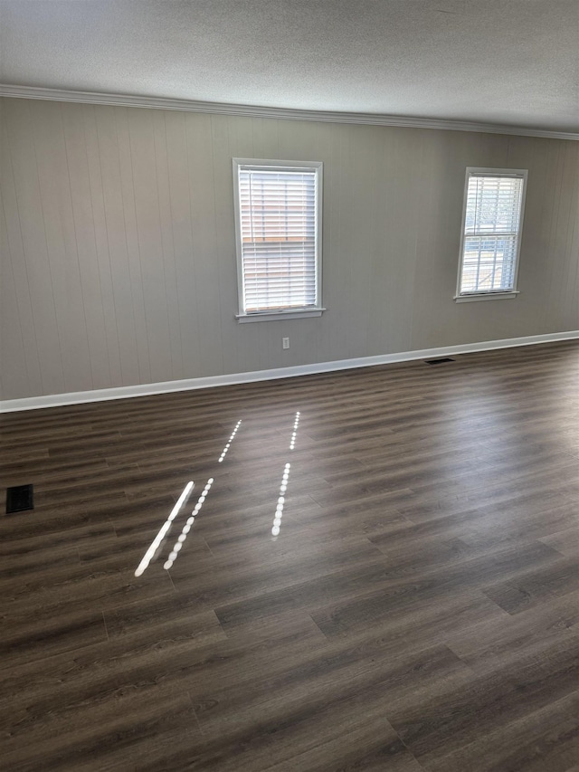 empty room with dark wood-type flooring, crown molding, visible vents, and a textured ceiling