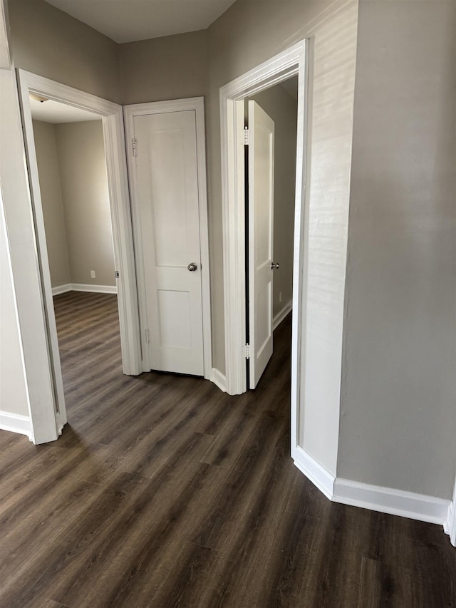 hall featuring baseboards and dark wood-style flooring