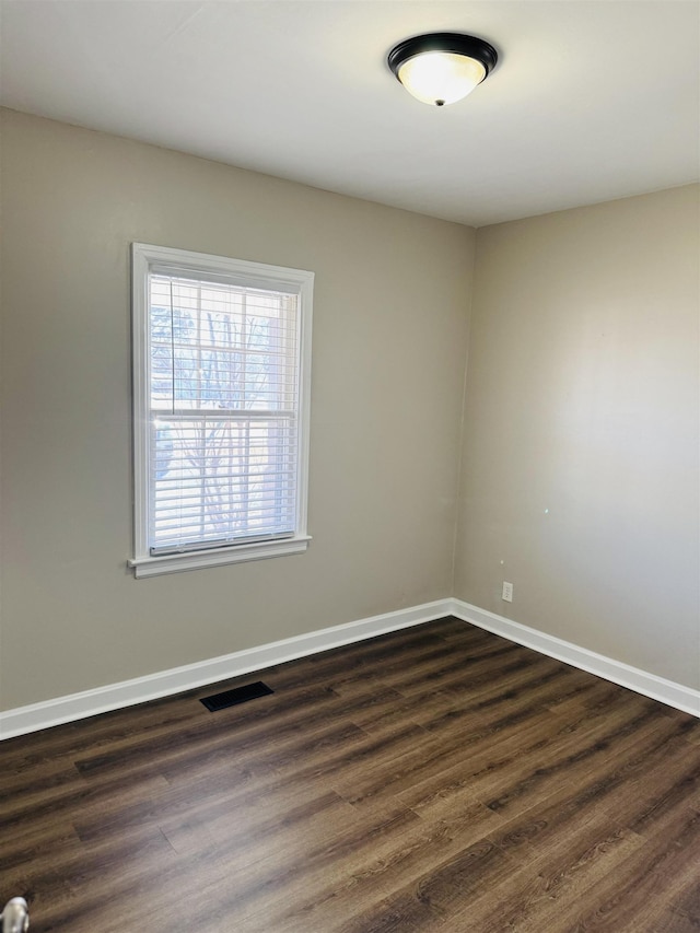 spare room featuring dark wood finished floors, baseboards, and visible vents