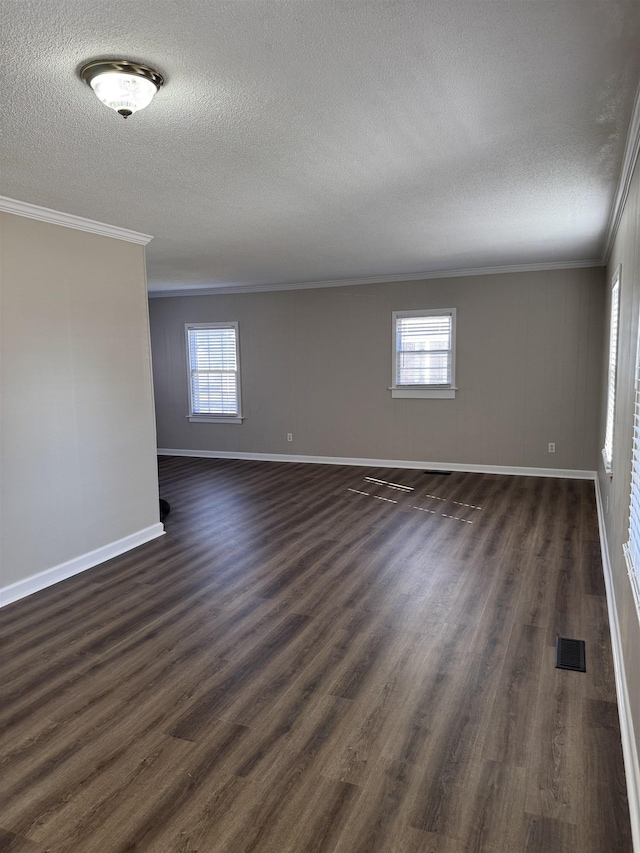 unfurnished room with visible vents, crown molding, dark wood-type flooring, baseboards, and a textured ceiling