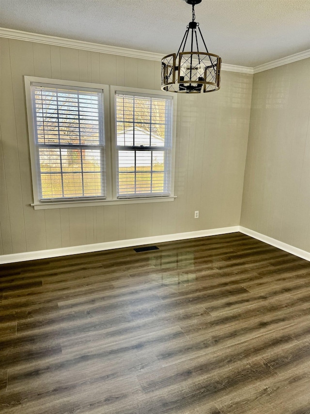 unfurnished dining area with visible vents, a notable chandelier, ornamental molding, dark wood finished floors, and baseboards