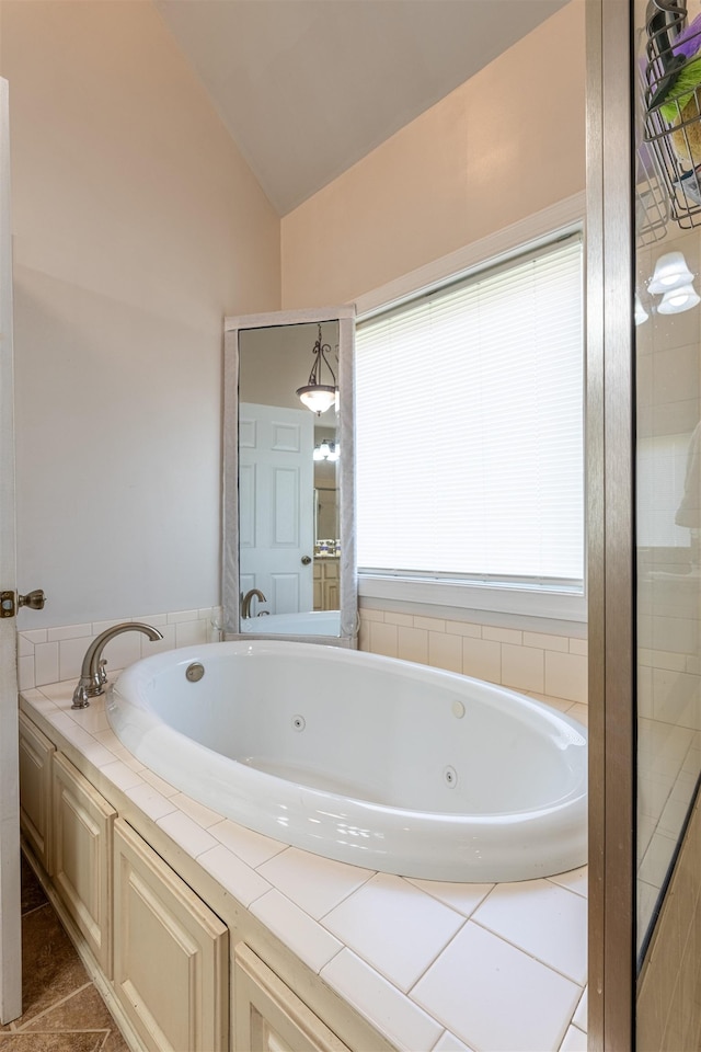  - full bath featuring lofted ceiling, a tub with jets, and tile patterned flooring