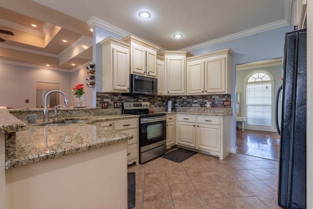  - kitchen featuring black appliances, tasteful backsplash, crown molding, light stone counters, and a peninsula