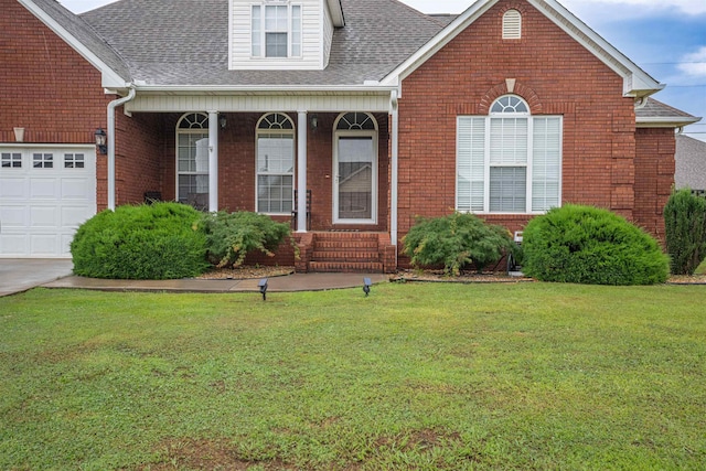  - view of front of home featuring a front yard, brick siding, roof with shingles, covered porch, and an attached garage