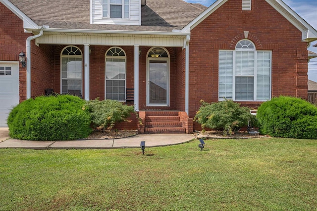  - view of front of property with a front yard, brick siding, entry steps, and roof with shingles